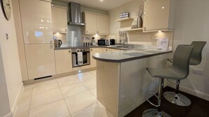 A modern kitchen with a central island, stainless steel appliances, and a bar stool. - ⭐ Luxury 5-Star Apartment with Panoramic Pannett Park Views & Parking (Whitby)