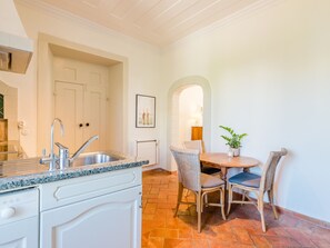 A kitchen with a sink, cabinets, and a dining area with a table and chairs. - Apartment  by Interhome (Bensafrim)