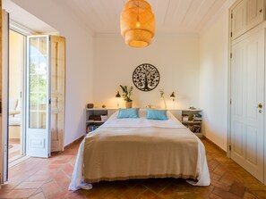 A bedroom with a large bed, a wall-mounted tree decoration, bedside tables with lamps, and a door leading to an outdoor area. - Apartment  by Interhome (Bensafrim)