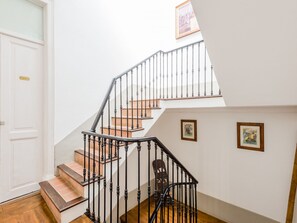 Un escalier muni d’une rampe, avec des marches en bois et une porte portant l’inscription « Arcade ».