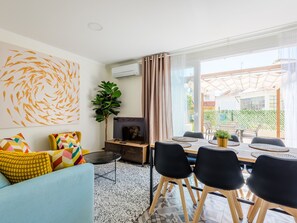 Ein modernes Wohnzimmer mit einer Couch, Fernseher und Essbereich mit Stühlen und einem Tisch.