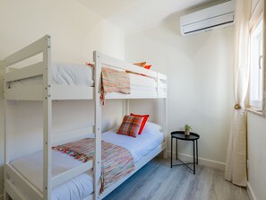 Ein Schlafraum mit Etagenbetten, einem kleinen Tisch und einer Klimaanlage.