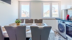 A modern kitchen with a built-in washing machine, a dining area with a table and chairs, and large windows with a city view. - Apartment  by Interhome (Lisbon)