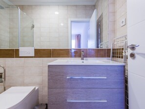Ein modernes Badezimmer mit Waschbecken, Spiegel und Dusche.