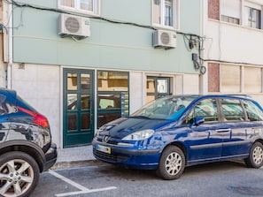 A blue station wagon parked in front of a building with a green door and a number '87' sign. - Apartment  by Interhome (Lisbon)