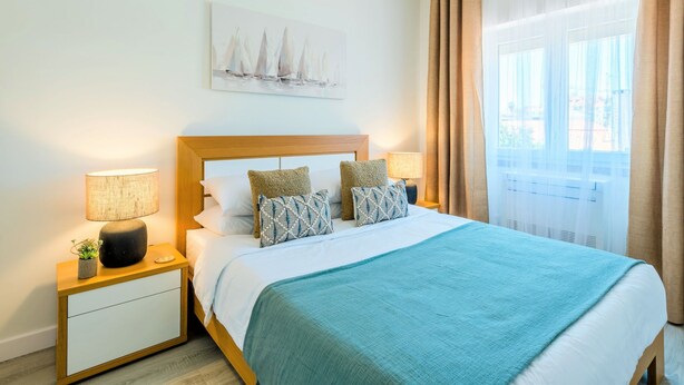 A hotel room with a bed, nightstands, a lamp, a painting, and a window with curtains. - Apartment  by Interhome (Lisbon)