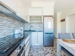 A modern kitchen with a built-in dishwasher, a stainless steel refrigerator, and a patterned backsplash. - Apartment  by Interhome (Lisbon)