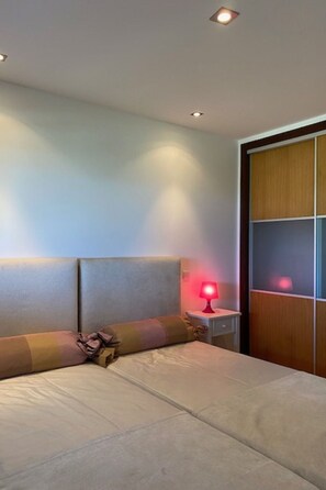A bedroom with a bed, a nightstand with a red lamp, and a wooden wardrobe. - Apartment  by Interhome (Alcobaça)