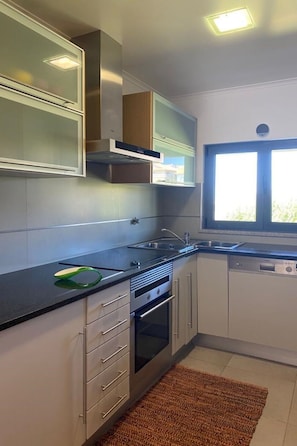 A modern kitchen with a built-in oven, a dishwasher, and a window providing natural light. - Apartment  by Interhome (Alcobaça)