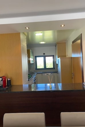 A modern kitchen with a central island, a window above the sink, and wooden cabinets. - Apartment  by Interhome (Alcobaça)
