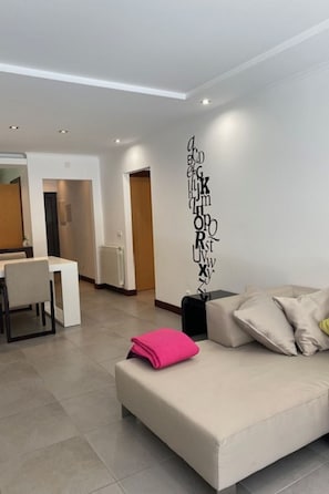 A modern living room with a sofa, a coffee table, and a wall with alphabet letters. There is a dining area in the background with a table and chairs. - Apartment  by Interhome (Alcobaça)