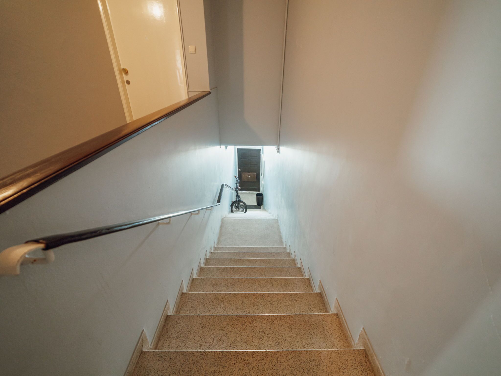 Una escalera con barandilla que lleva a una puerta al final.