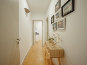 A hallway with a wooden console table, framed pictures on the wall, and a door leading to a bathroom. - Apartment  by Interhome (Porto)