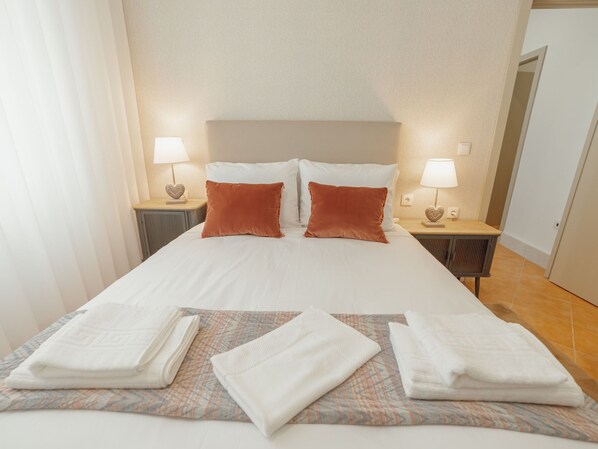 Une chambre d’hôtel avec un grand lit, deux tables de chevet, deux lampes et une porte.