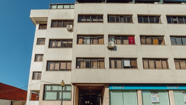 A multi-story building with a ground-level entrance, a staircase leading to the entrance, and a sign indicating a business on the ground floor. - DOWNTOWN STYLISH APARTMENT & GARAGE by VACATIONY by Interhome (Porto)