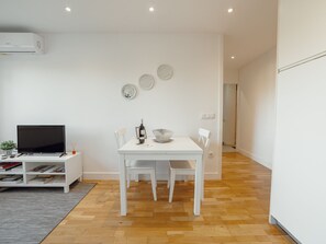 A modern living room with a flat-screen TV, a dining table with chairs, and a small side table with a plant. - DOWNTOWN STYLISH APARTMENT & GARAGE by VACATIONY by Interhome (Porto)