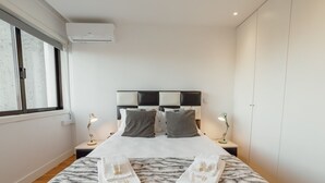 A hotel room with a bed, two bedside lamps, a window, and a wardrobe. - DOWNTOWN STYLISH APARTMENT & GARAGE by VACATIONY by Interhome (Porto)