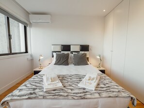 A hotel room with a bed, two bedside lamps, a window, and a wardrobe. - DOWNTOWN STYLISH APARTMENT & GARAGE by VACATIONY by Interhome (Porto)