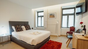 Un dormitorio moderno con una cama grande, un escritorio, una silla y una alfombra roja.