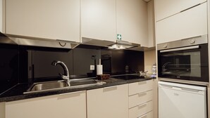 Una cocina moderna con horno empotrado, un lavamanos y una campana extractora.
