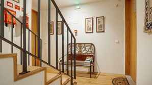 Una escalera con barandilla de madera y balaustres negros que lleva a una habitación con una cama y una alfombra pequeña.