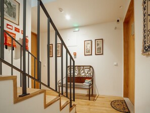 A staircase with a wooden handrail and black balusters, leading to a room with a bed and a small rug. - Apartment  by Interhome (Porto)