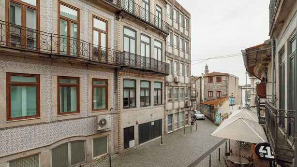 Una estrecha calle adoquinada flanqueada por edificios de varios pisos con balcones ornamentados y fachadas decorativas.