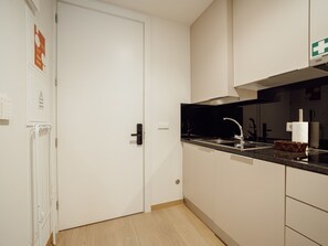 A modern kitchen with a black countertop, stainless steel sink, and a white door. - Apartment  by Interhome (Porto)
