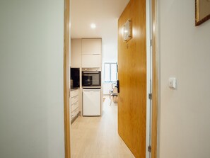 A narrow hallway leading to a kitchen with a refrigerator, oven, and cabinets. - Apartment  by Interhome (Porto)