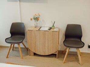 Two black chairs with wooden legs, a wooden desk with a vase of flowers, a remote control, and a small green object on the desk. - Apartment  by Interhome (Porto)