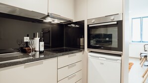 Moderni keittiö, jossa on sisäänrakennettu uuni, työtaso ja viinipullo.