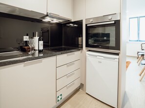 A modern kitchen with a built-in oven, a countertop, and a wine bottle. - Apartment  by Interhome (Porto)