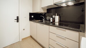 Moderni keittiö, jossa on musta työtaso, ruostumattomasta teräksestä valmistetut kodinkoneet ja vaaleat keittiökaapit.