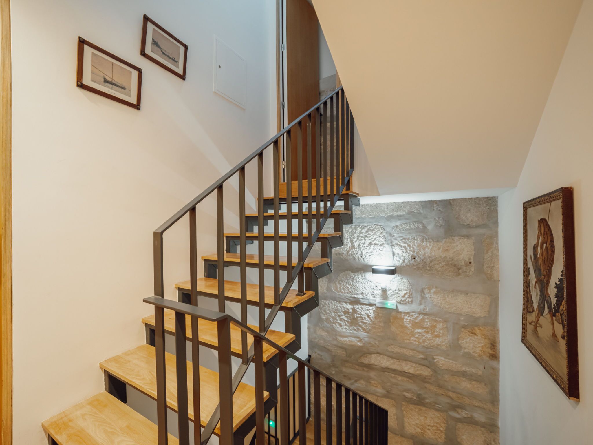 A staircase with wooden steps and metal railings, leading to a stone wall.