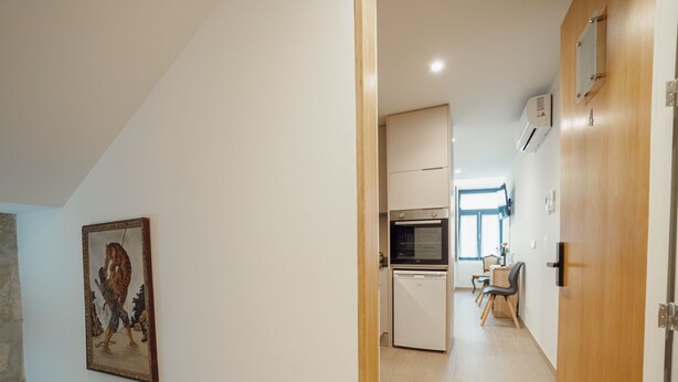 Ein Flur, der zu einer Küche mit Essbereich führt, ein Gemälde an der Wand und eine Holztür.