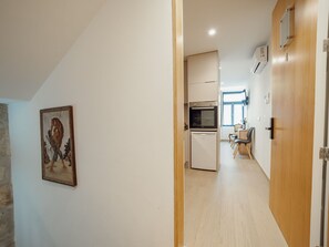 Ein Flur, der zu einer Küche mit Essbereich führt, ein Gemälde an der Wand und eine Holztür.