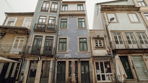 Eine Reihe mehrstöckiger Gebäude mit Balkonen, im Erdgeschoss ein Restaurant namens 'Casa do Carmo', und eine gepflasterte Straße.