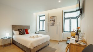 Ein modernes Schlafzimmer mit Bett, Nachttisch, Lampe und Schreibtisch mit Stuhl.
