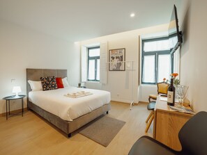 Ein modernes Schlafzimmer mit Bett, Nachttisch, Lampe und Schreibtisch mit Stuhl.