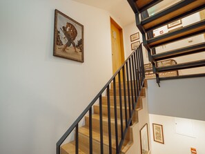 Eine Treppe mit schwarzem Metallgeländer, Holzstufen und einem gerahmten Bild an der Wand.