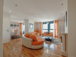 Ein modernes Wohnzimmer mit einer gebogenen Couch, einem Couchtisch und einem Hängekorbsessel.