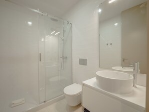 A modern bathroom with a glass-enclosed shower, a toilet, and a sink with a mirror. - Apartment  by Interhome (Porto)