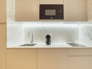 A modern kitchen with a built-in microwave, a coffee maker, and a double sink. - Apartment  by Interhome (Porto)