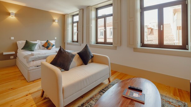 Ett modernt hotellrum med en säng, en soffa, ett soffbord och stora fönster.