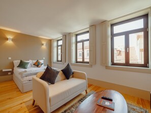 A modern hotel room with a bed, a sofa, a coffee table, and large windows. - Apartment  by Interhome (Porto)