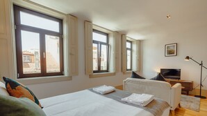 Ett hotellrum med en säng, en tv och ett skrivbord med en lampa.