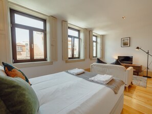 A hotel room with a bed, a television, and a desk with a lamp. - Apartment  by Interhome (Porto)