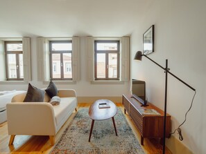 A modern living room with a sofa, a coffee table, a TV, and a floor lamp. - Apartment  by Interhome (Porto)