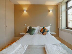 Una habitació d'hotel amb un llit, dues taules de nit, una finestra i un armari.