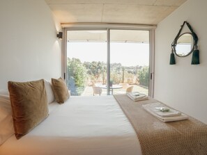 Ein Schlafzimmer mit einer großen Schiebeglasdoor, die zu einem Außenbereich mit Tisch und Stühlen führt.